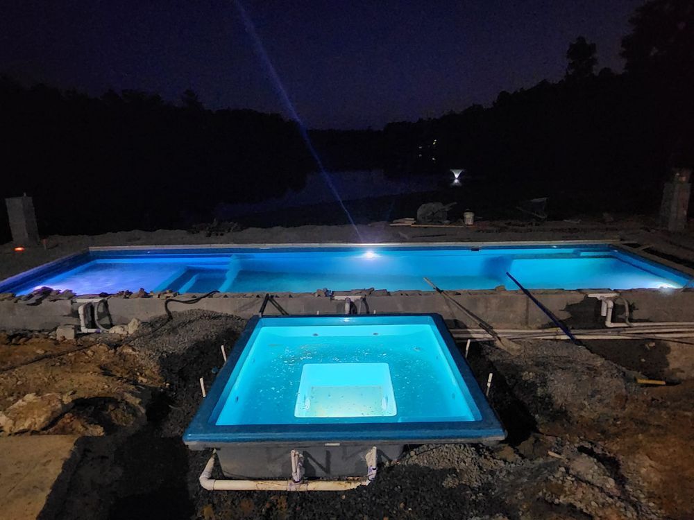 A large swimming pool is being built at night.