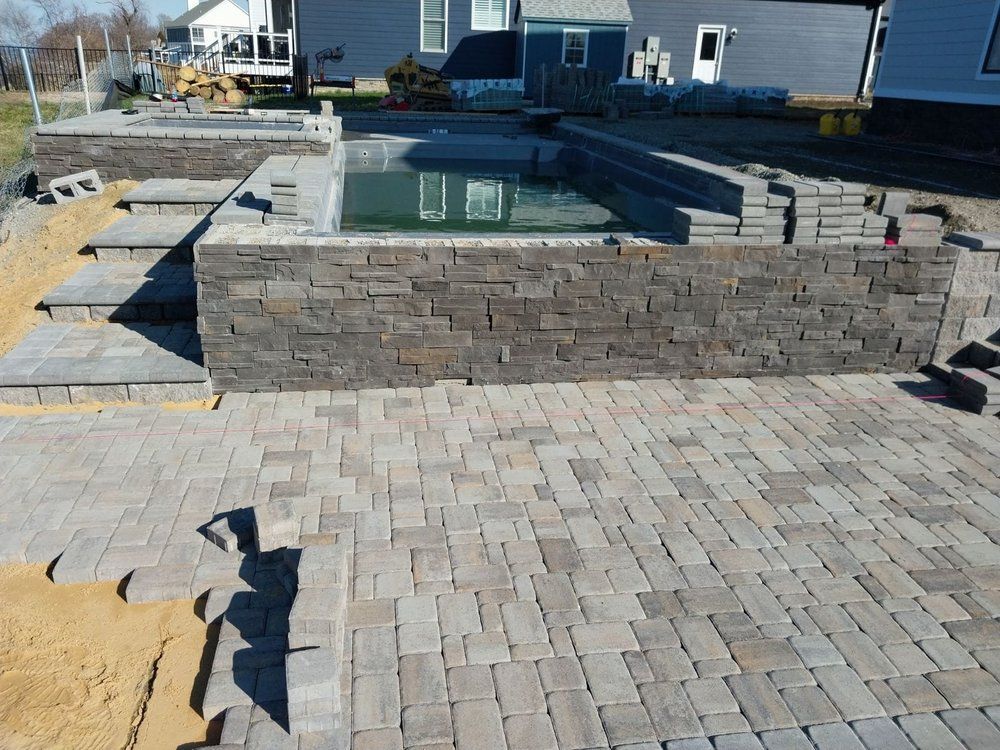 A brick patio with a swimming pool in the background