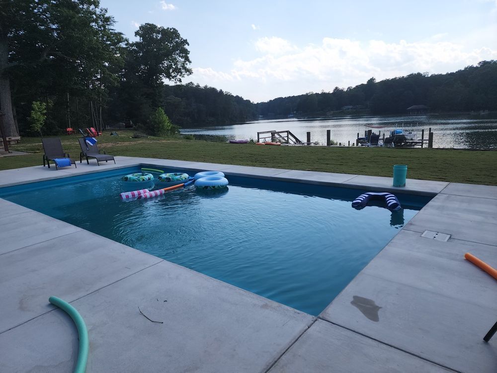 A large swimming pool with a lake in the background