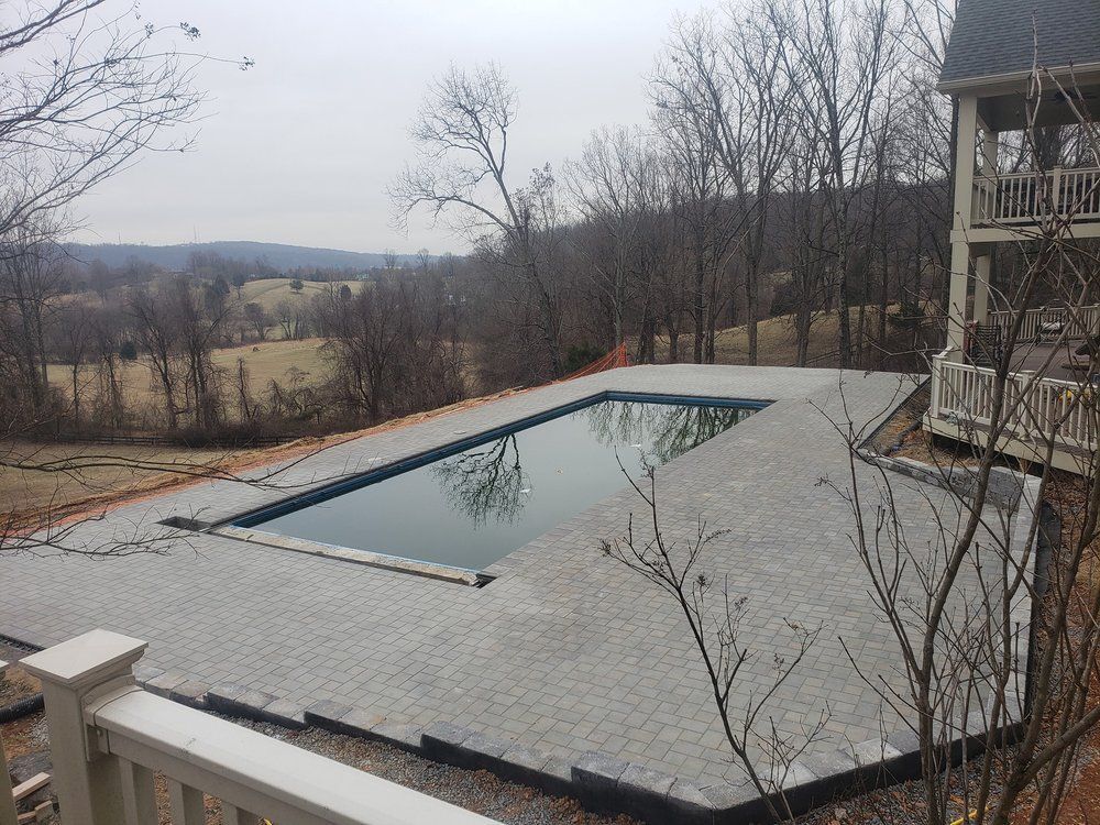 A large swimming pool is in the backyard of a house.