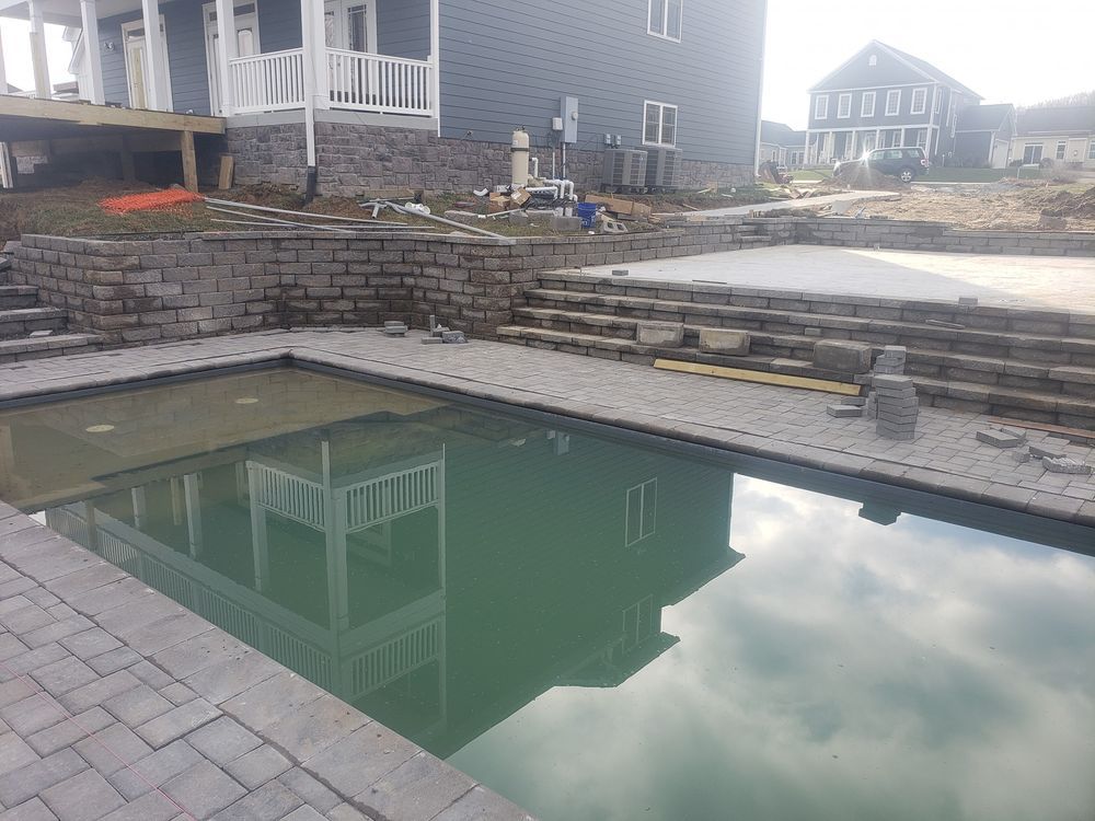 A large swimming pool with a house in the background is being built.
