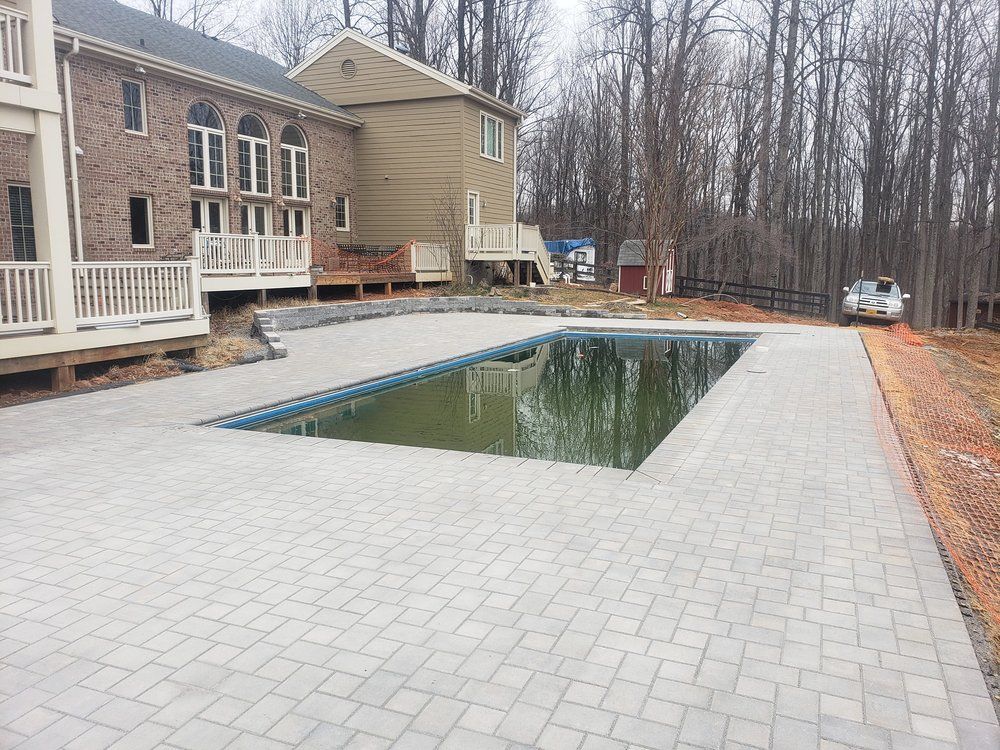 A large swimming pool is in the backyard of a house.
