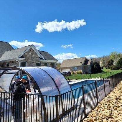 A man is standing in front of a pool with a canopy over it