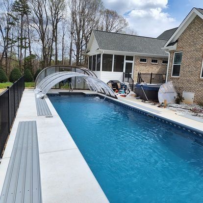 A large swimming pool in front of a brick house
