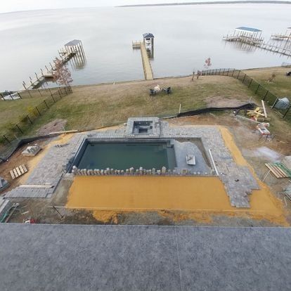 An aerial view of a swimming pool being built next to a body of water