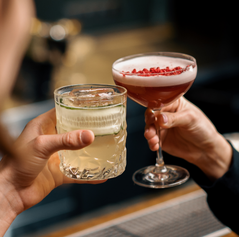 Two people are toasting with two different drinks in their hands