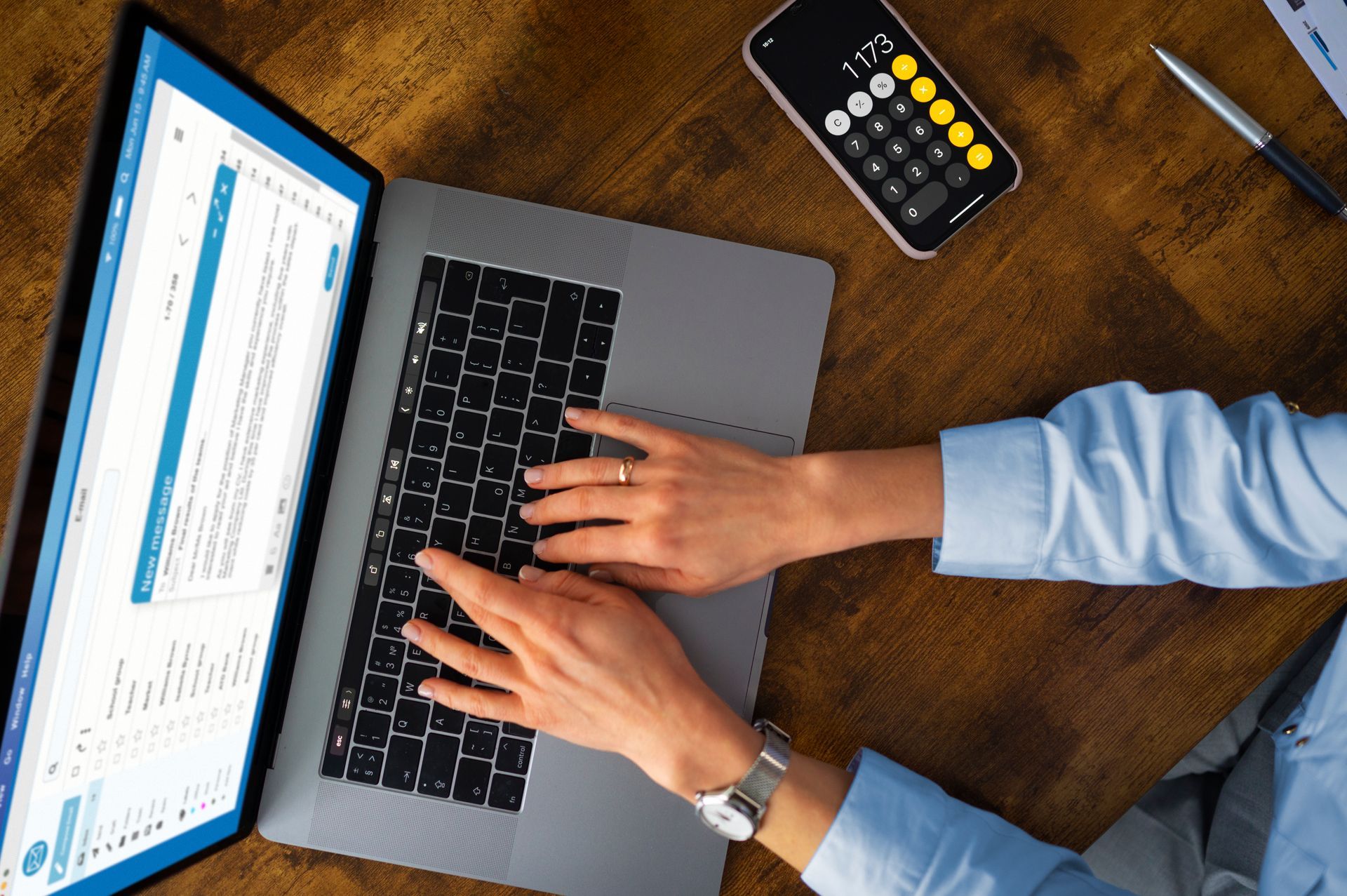 Uma pessoa fazendo cálculos no notebook com um celular ao lado