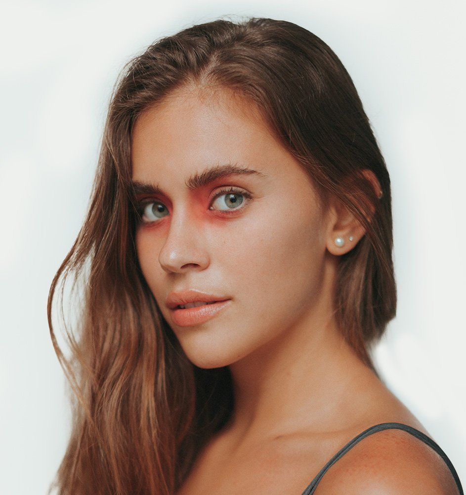 Woman with red eye makeup, gazing toward the camera with light eyes and a neutral expression.