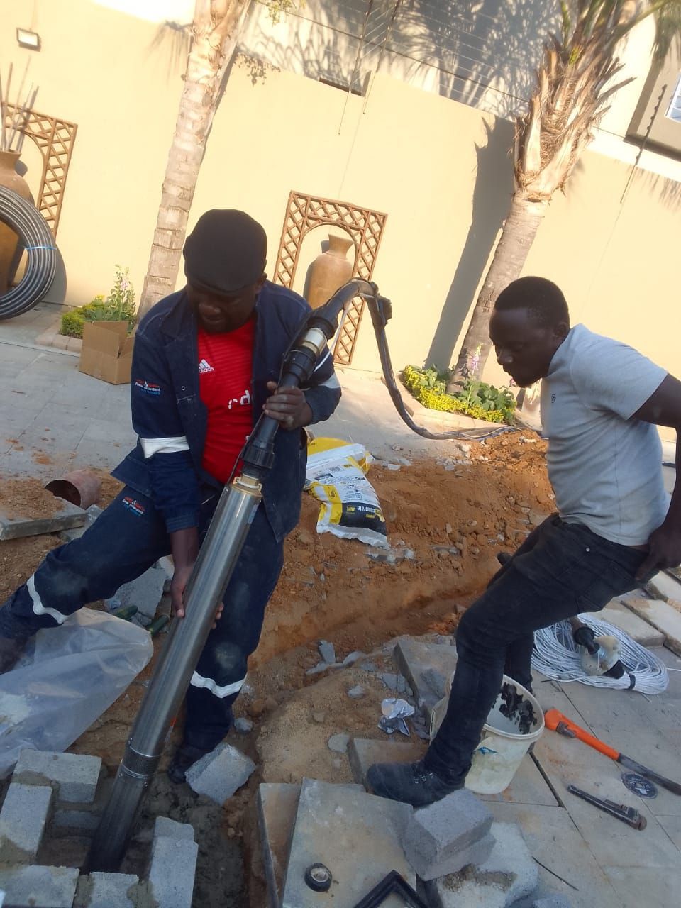 two men are working on a pump in the dirt