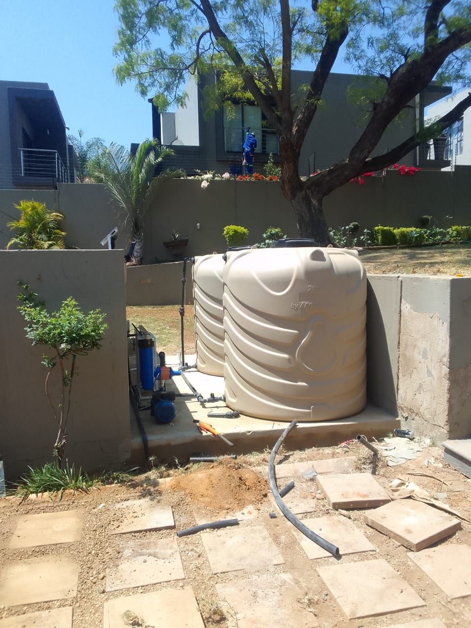 a large water tank is sitting next to a tree in a backyard