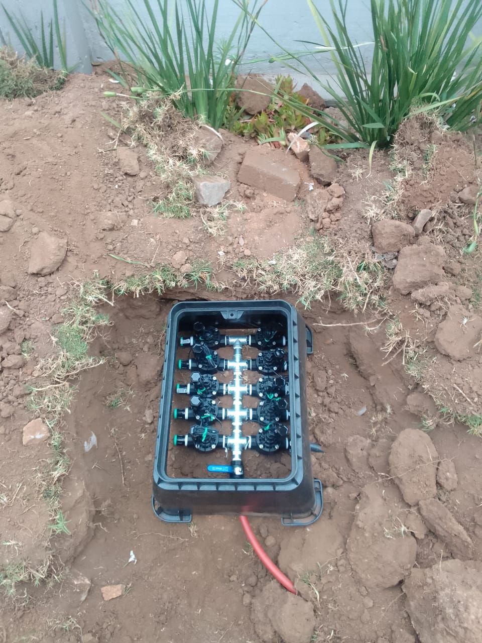 a box filled with sprinkler tap system sitting in the dirt