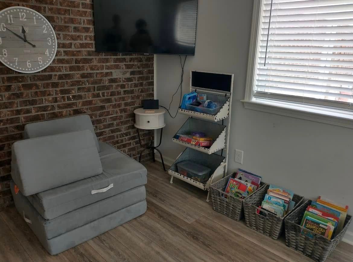 Gray play couch in a brick-walled room with a TV, bookshelf, and window.