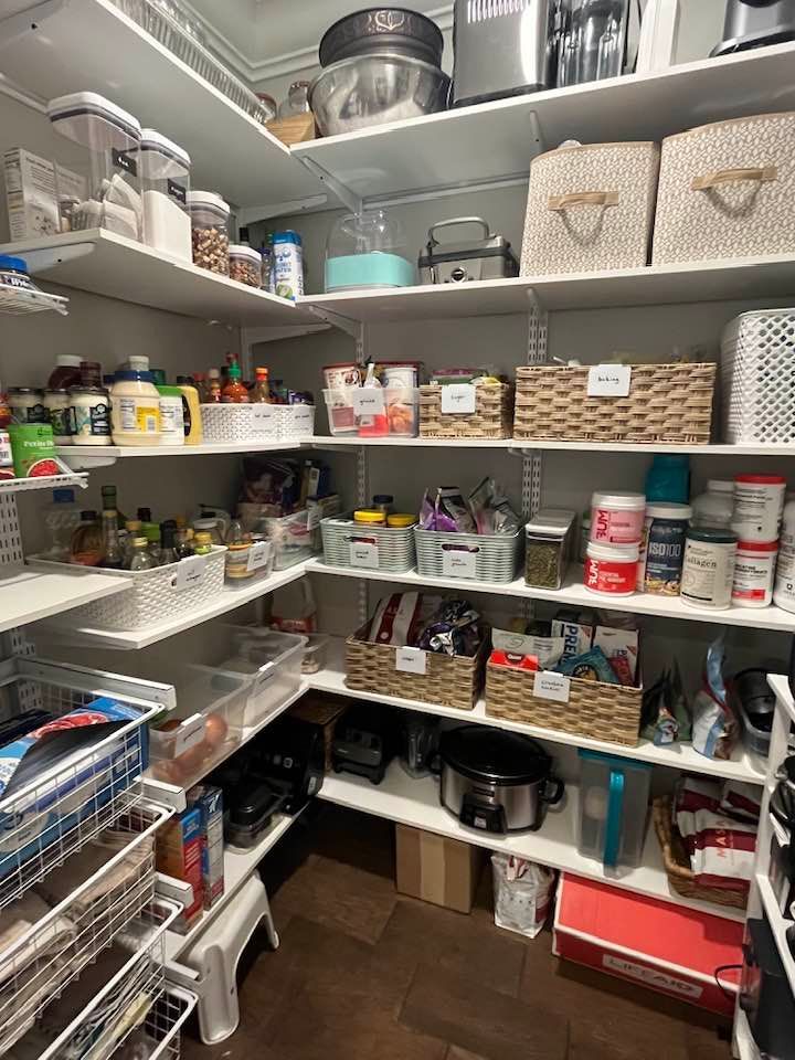 Organized pantry with white shelving, baskets, and various food items.
