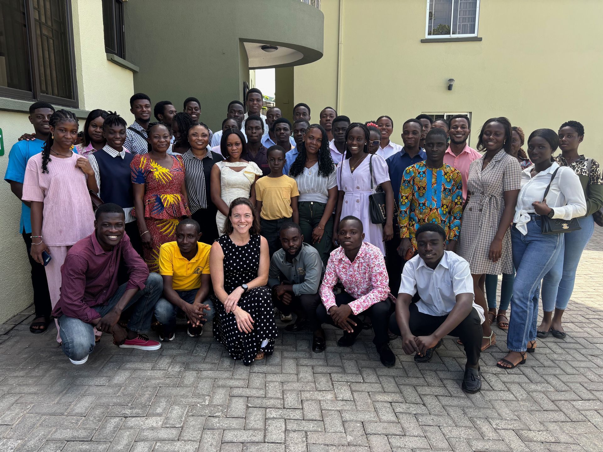 Group of people posing outdoors in front of a building.