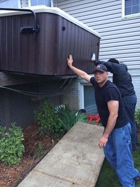 Two men are pushing a hot tub down a sidewalk