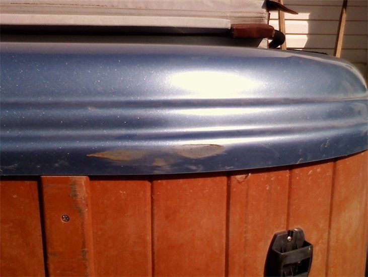 A wooden hot tub with a blue cover on top of it