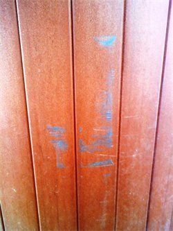 A close up of a wooden wall with a blue stain on it.