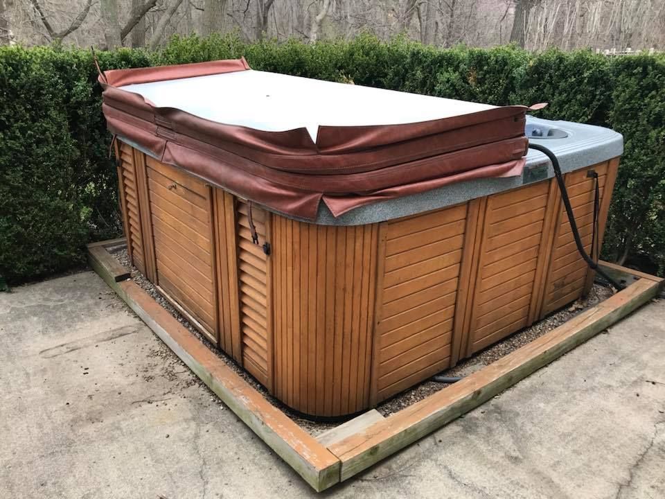 A wooden hot tub with a red cover on it