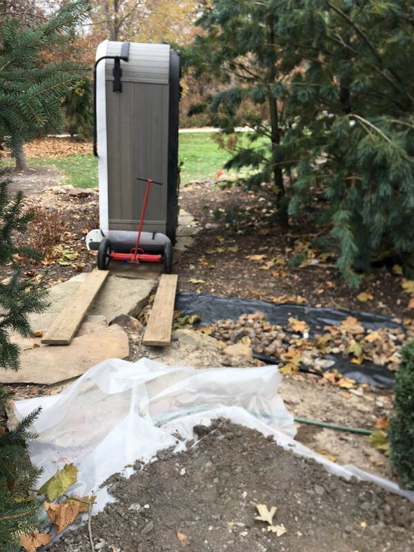 A hot tub is being moved on a dolly in the woods.