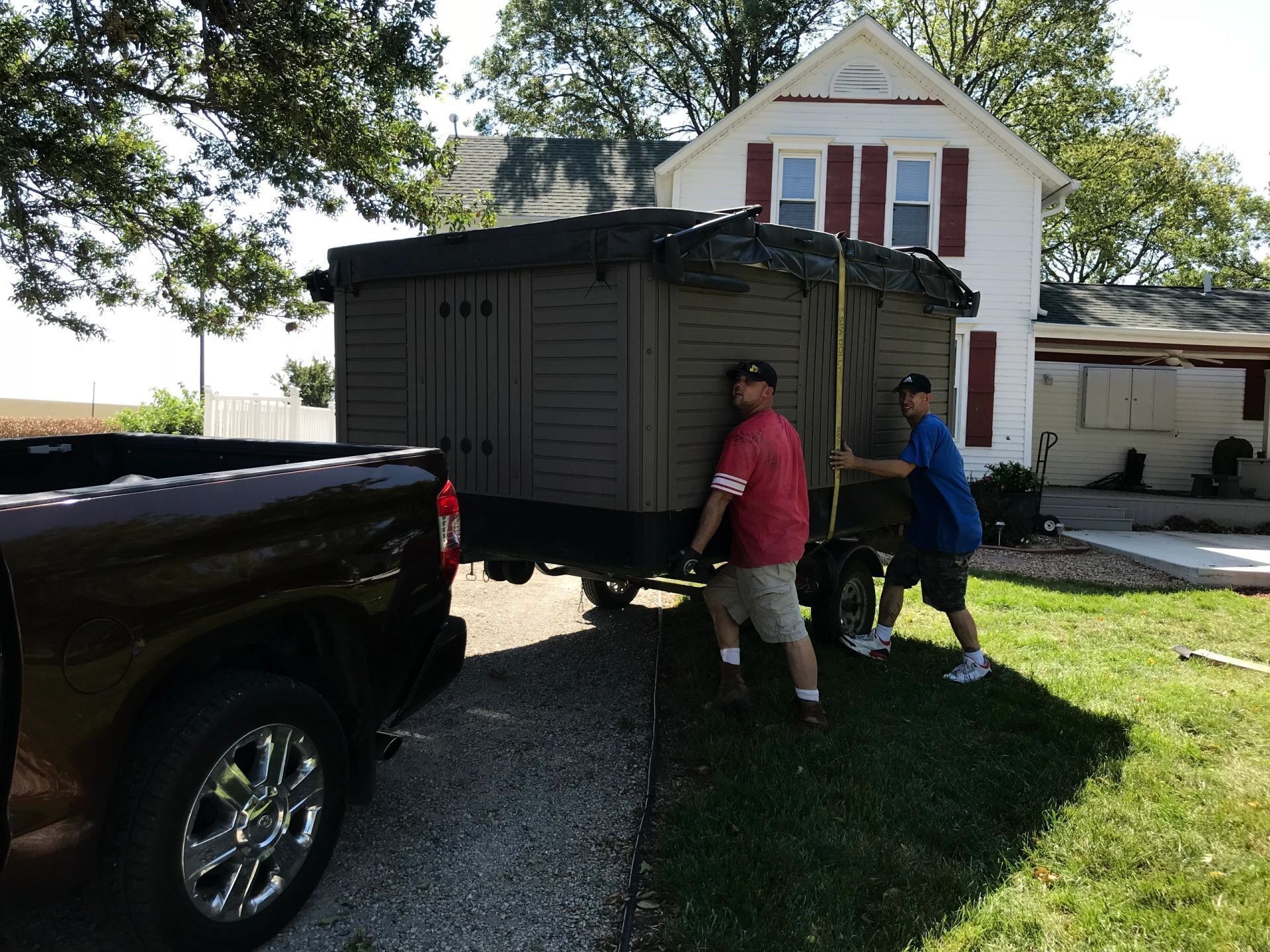 Two men are loading a shed into a truck