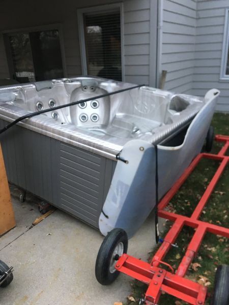 A hot tub is sitting on a cart outside of a house