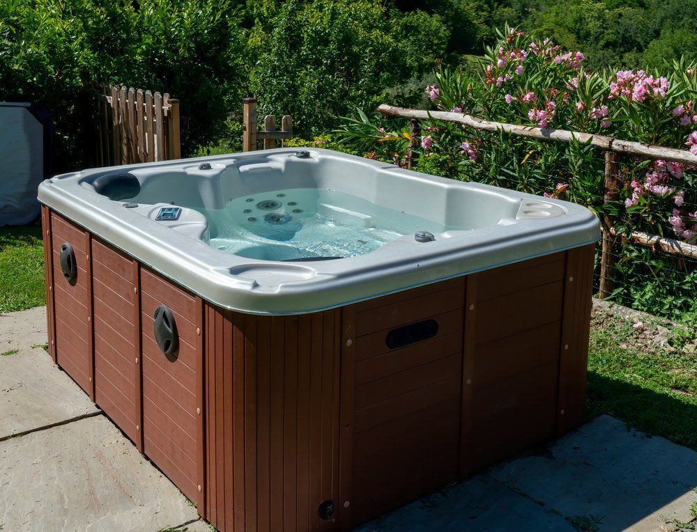 A hot tub is sitting on a patio with a fence in the background