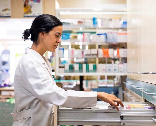 a female pharmacist is working in a pharmacy .