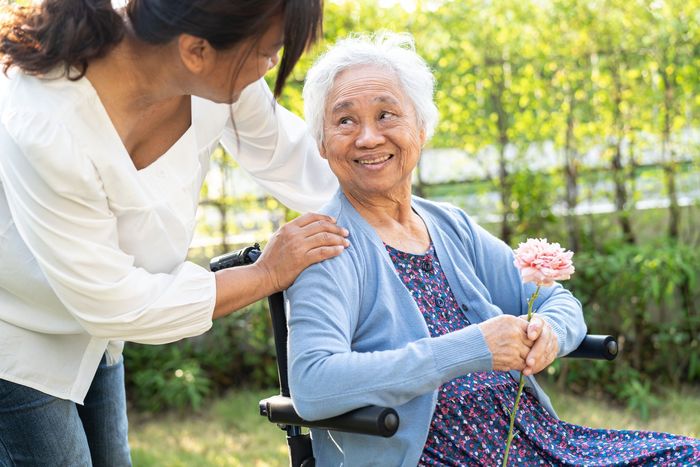 a woman is giving an elderly woman in a wheelchair a flower .