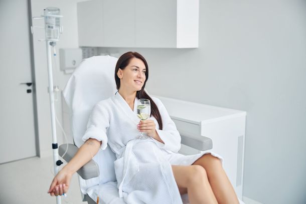 a woman is sitting in a hospital bed holding a glass of wine .