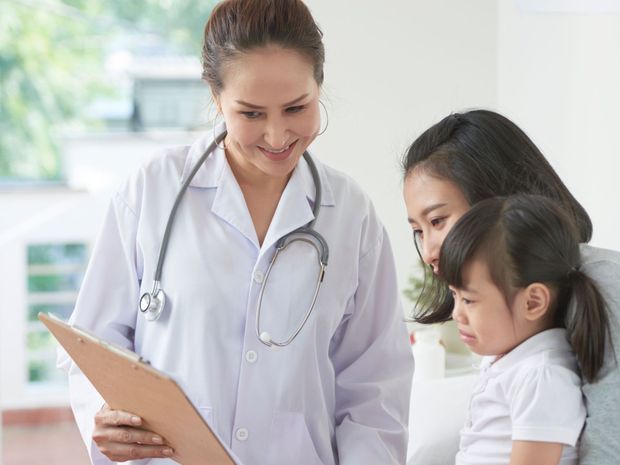 a doctor is talking to a little girl while holding a clipboard .