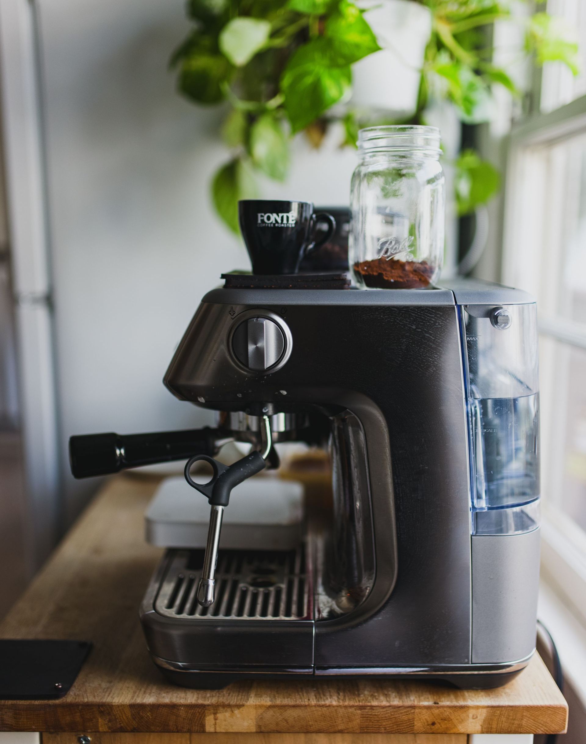 A coffee machine is sitting on a wooden table next to a window.