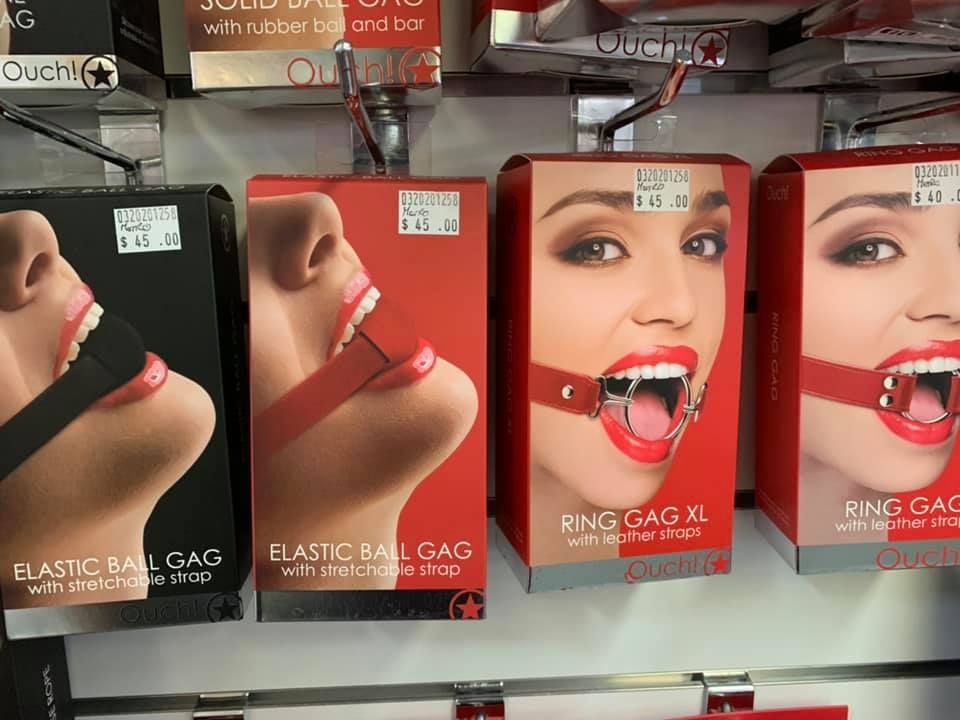 Retail display of packaged bondage mouth gags, including elastic ball gags and ring gags, hanging on store pegs — A Bit Cheeky The Adult Store In Lismore, NSW