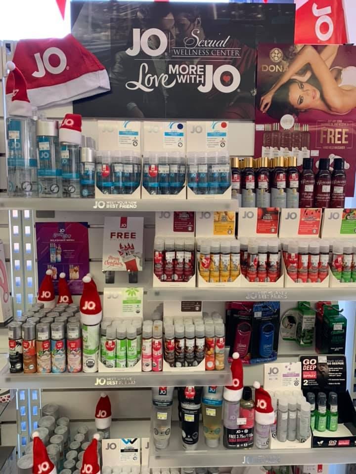 Store shelves stocked with various JO brand personal lubricant bottles, some adorned with small festive Santa hats — A Bit Cheeky The Adult Store In Lismore, NSW