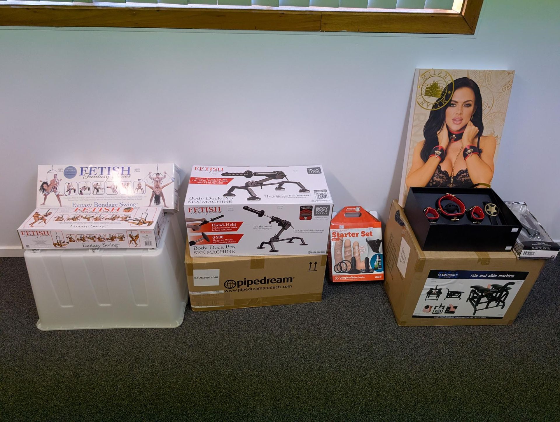 Several product boxes, including adult novelty items and a display featuring a model, arranged against a wall — A Bit Cheeky The Adult Store In Lismore, NSW