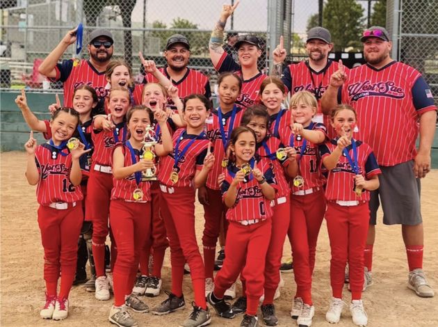 Baseball glove with ball on green grass, with blurred baseballs in the background.