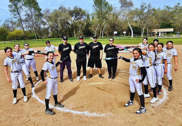 Baseball glove with ball on green grass, with blurred baseballs in the background.