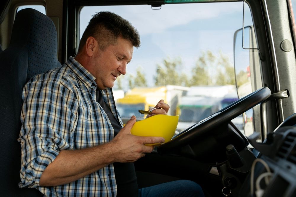 a man is sitting in the driver 's seat of a truck eating a delicious meal.