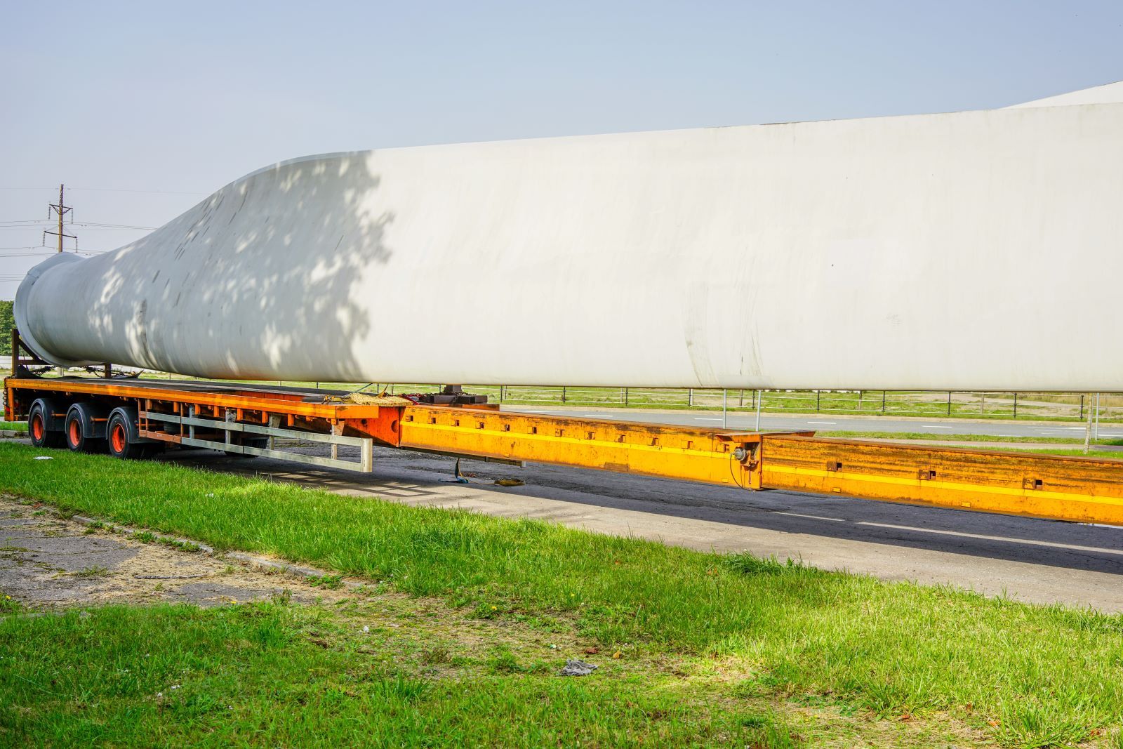 a large wind turbine is being transported on a trailer .