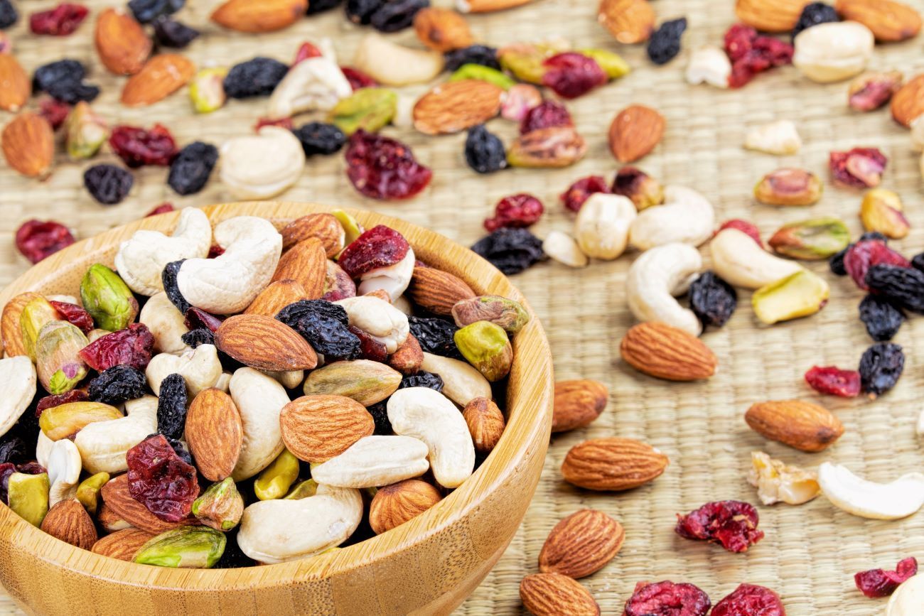 a wooden bowl filled with nuts and raisins on a table .