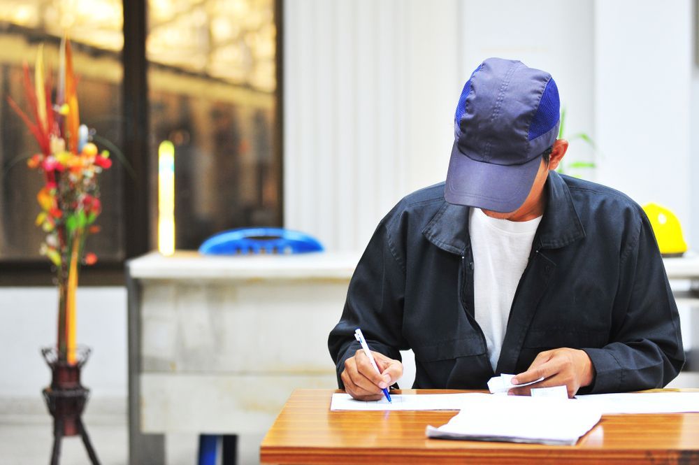a man wearing a blue hat is writing on a piece of paper