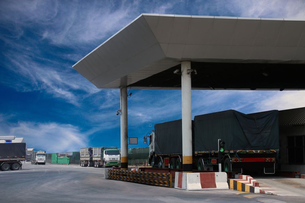 a lot of trucks are parked under a canopy at a gas station