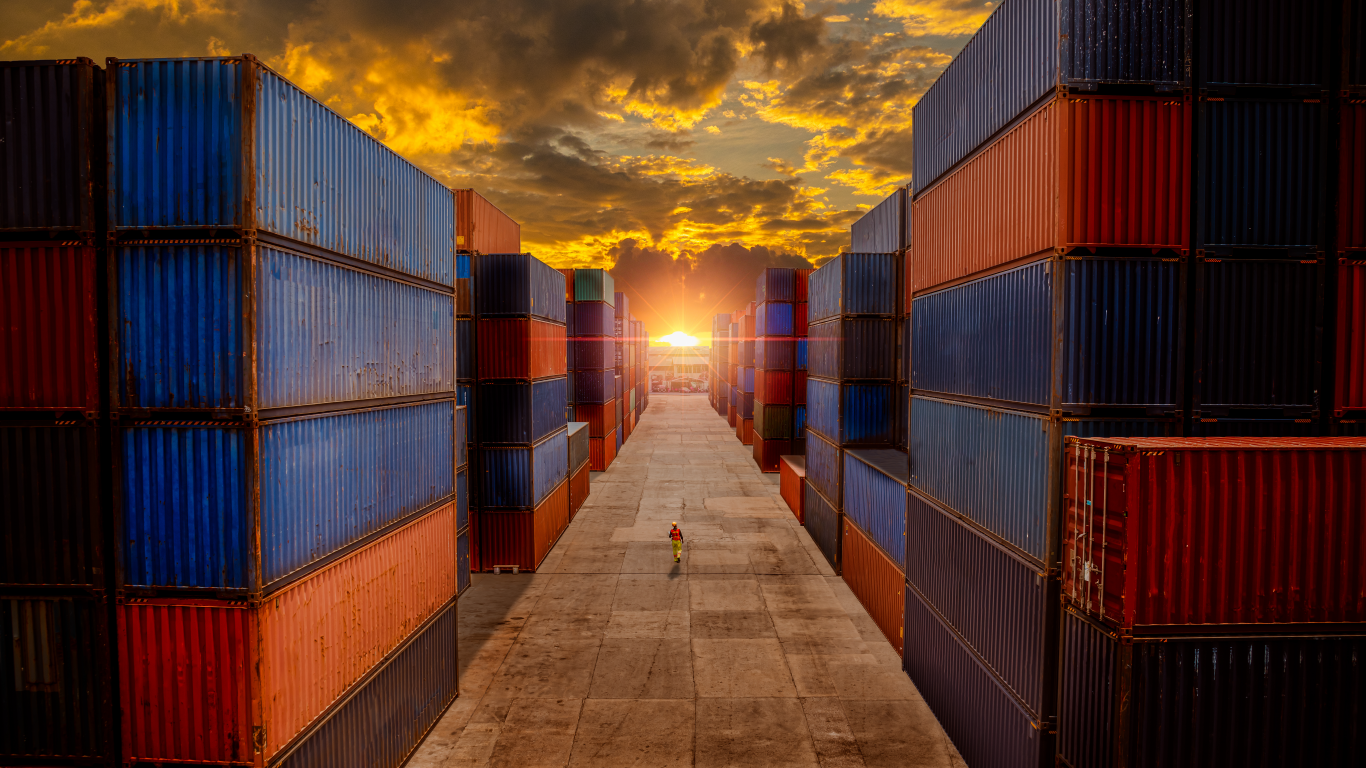 a row of shipping containers stacked on top of each other on a dock at sunset .