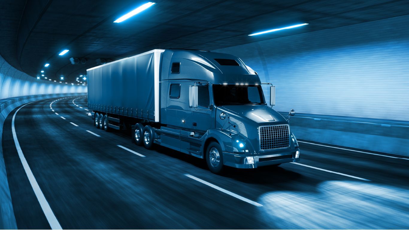 a semi truck is driving down a highway in a tunnel .