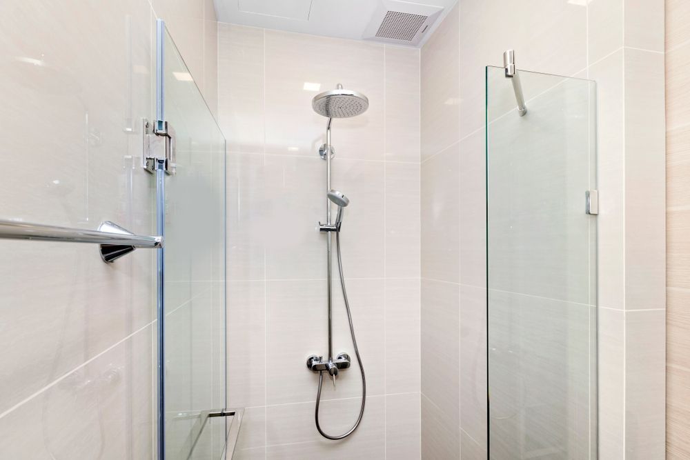 a truck stop bathroom with a walk in shower with a glass door and a shower head.