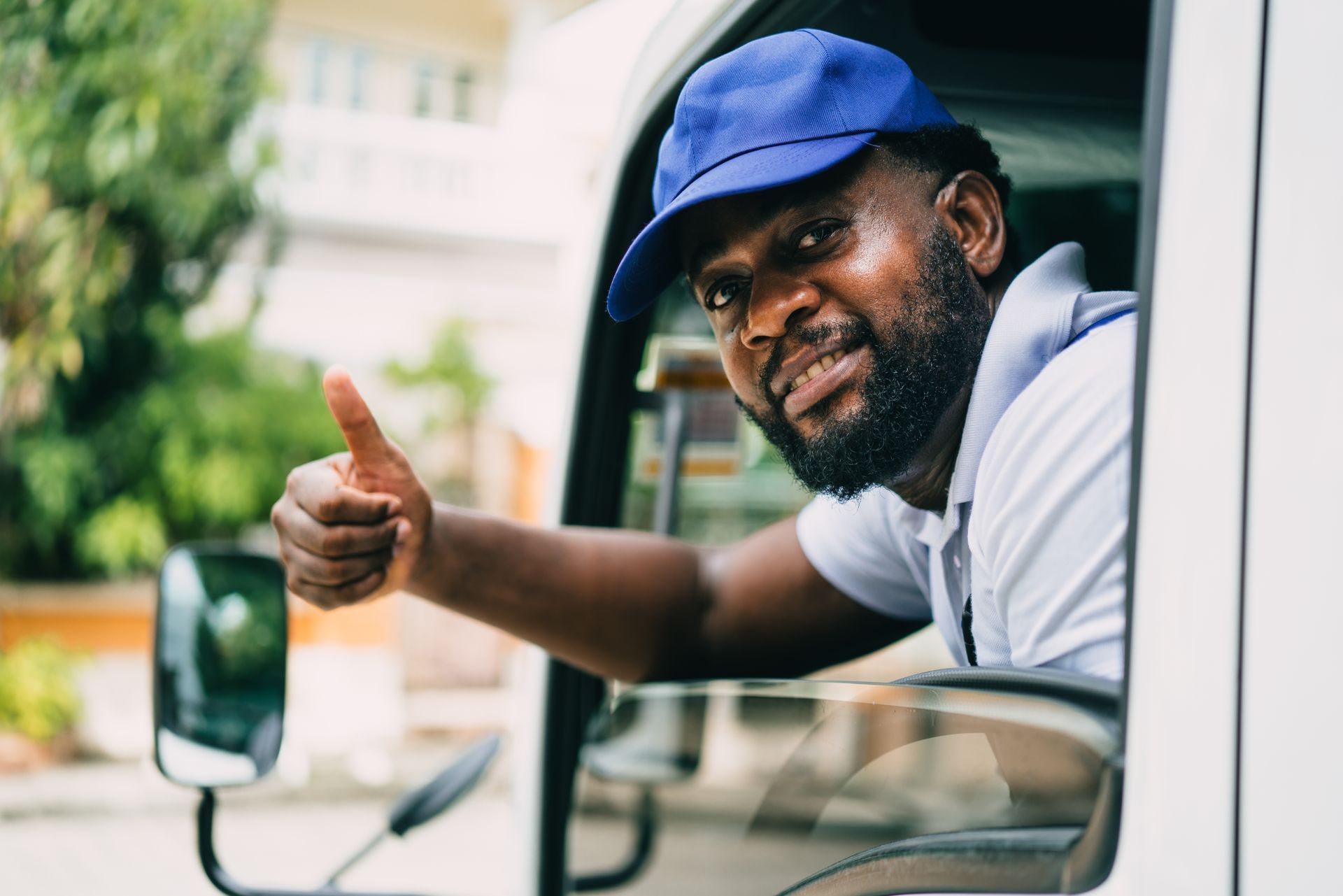 a man is giving a thumbs up while sitting in the driver 's seat of a truck .