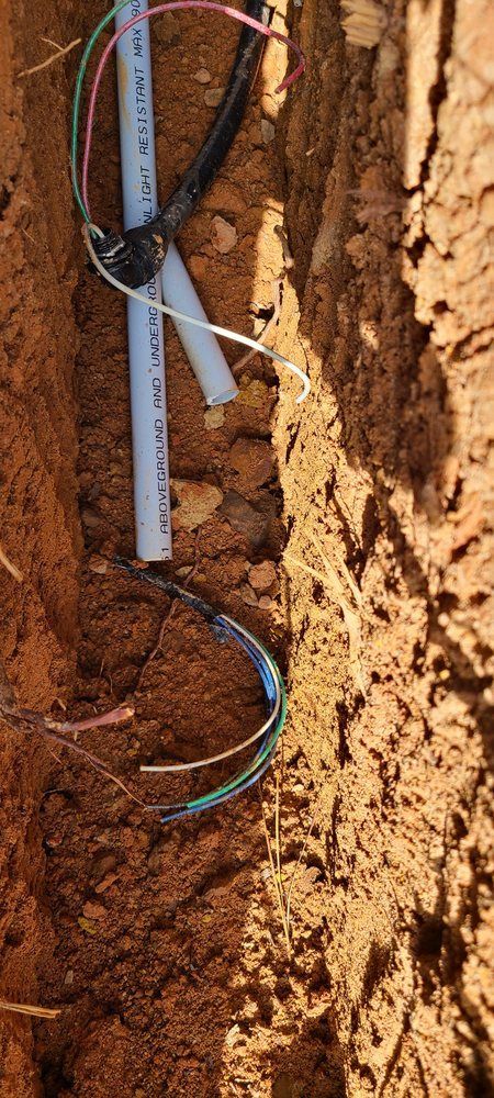 A bunch of wires are connected to a pipe in the dirt.