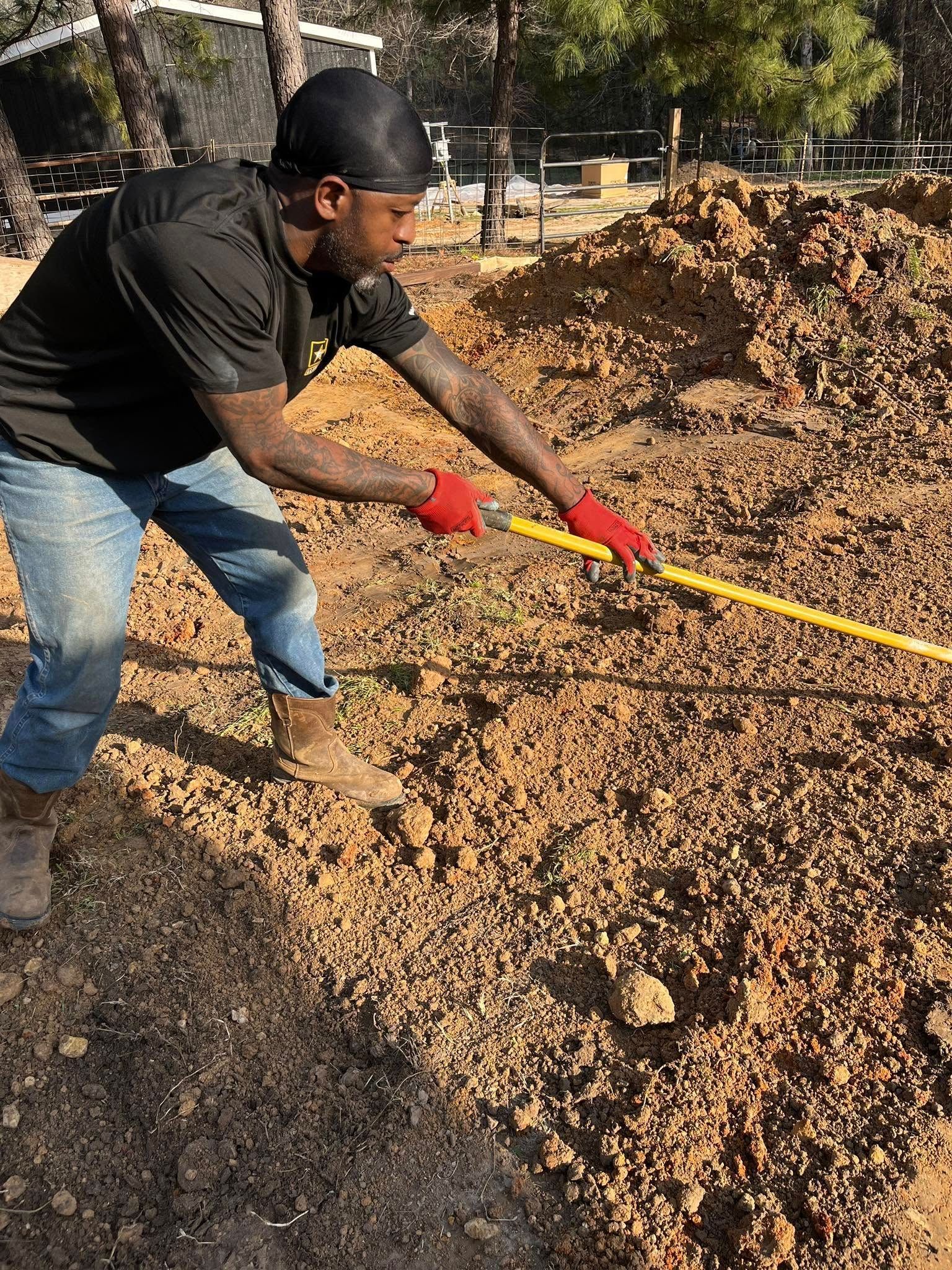 A man is measuring a pile of dirt with a tape measure.