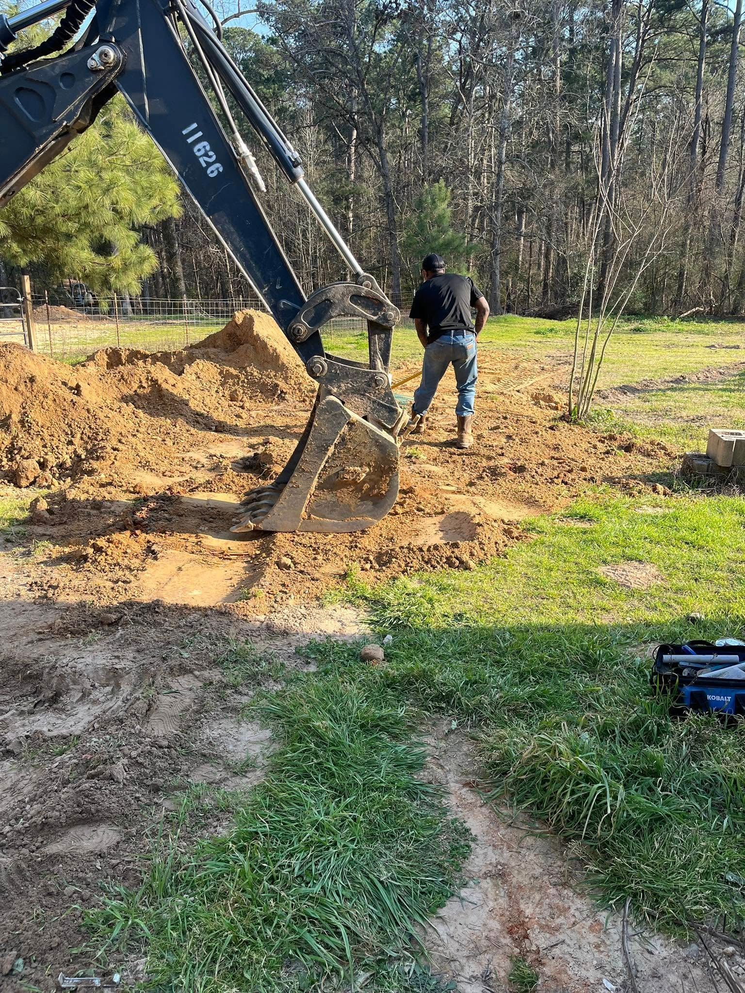 A man is digging a hole in the dirt with an excavator.