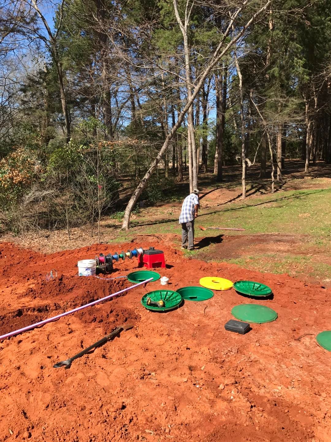 A man is standing in the dirt next to a tree.
