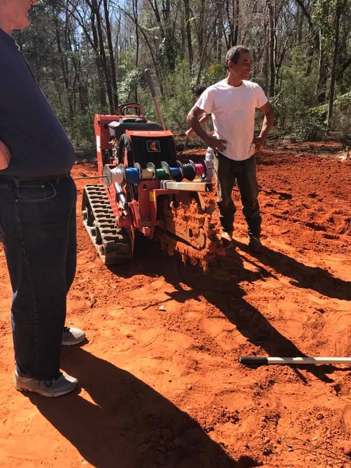 Two men are standing next to a tractor in the dirt.